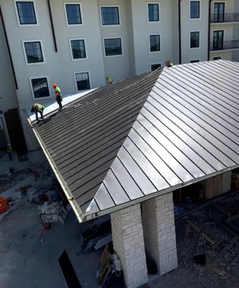 Crew installing standing seam metal roof panels on a commercial project in Pevely